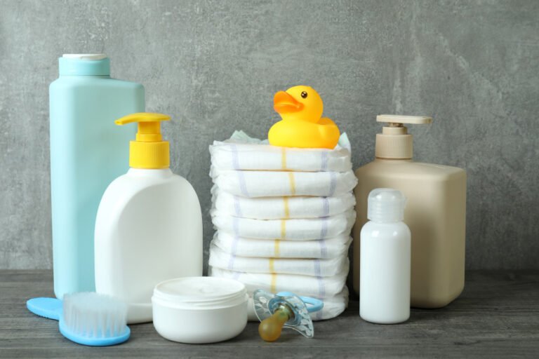 Natural and reusable baby products including cloth diapers, glass bottles, and organic cotton clothes displayed neatly on a baby mat.