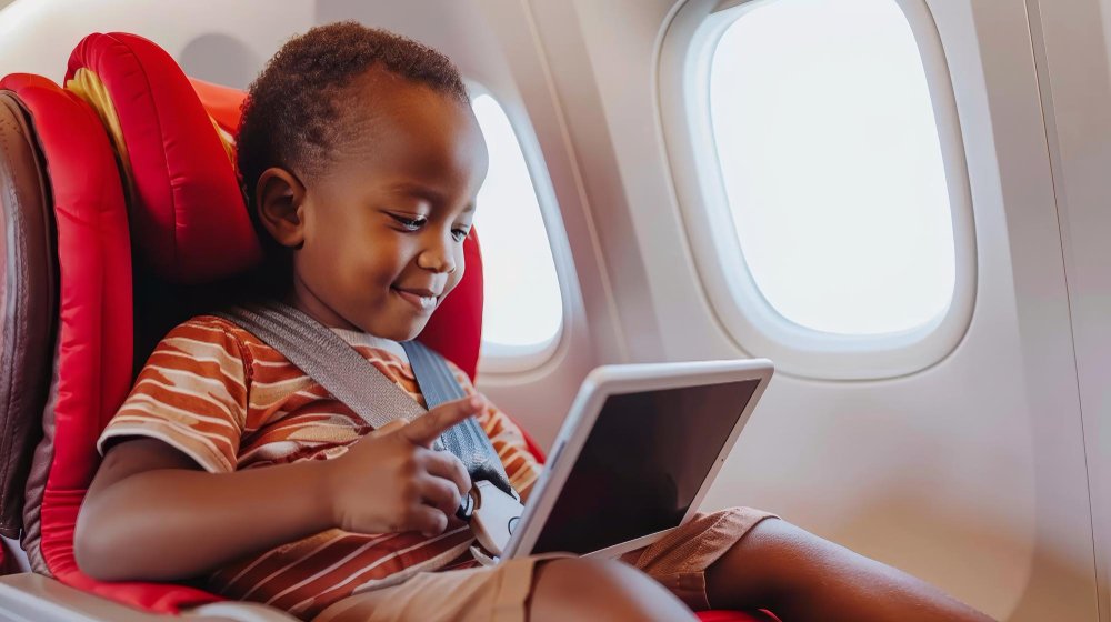 A Kenyan mother holding her baby while preparing for a road trip with a car seat and baby bag.